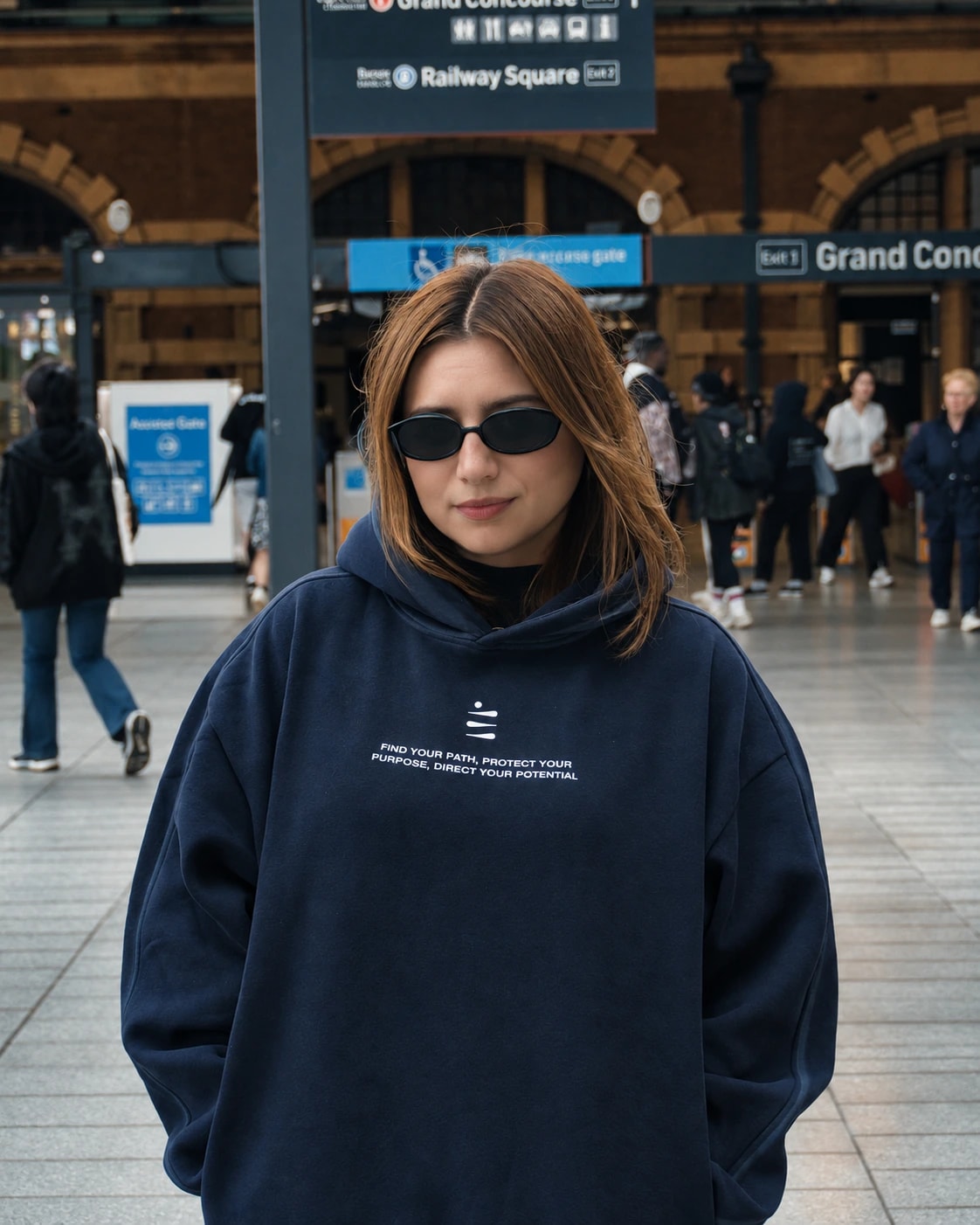 Mayte wearing a navy DIV3NITY hoodie and sunglasses at a train station