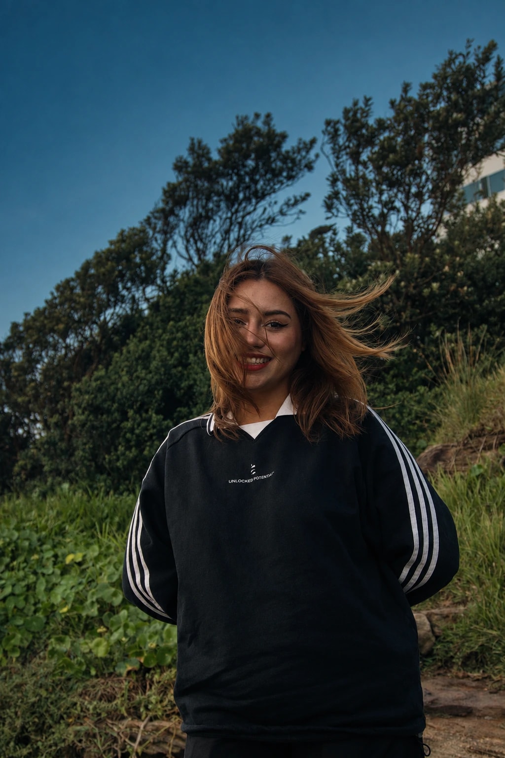 Mayte smiling in the coastal wind, wearing a black DIV3NITY jersey